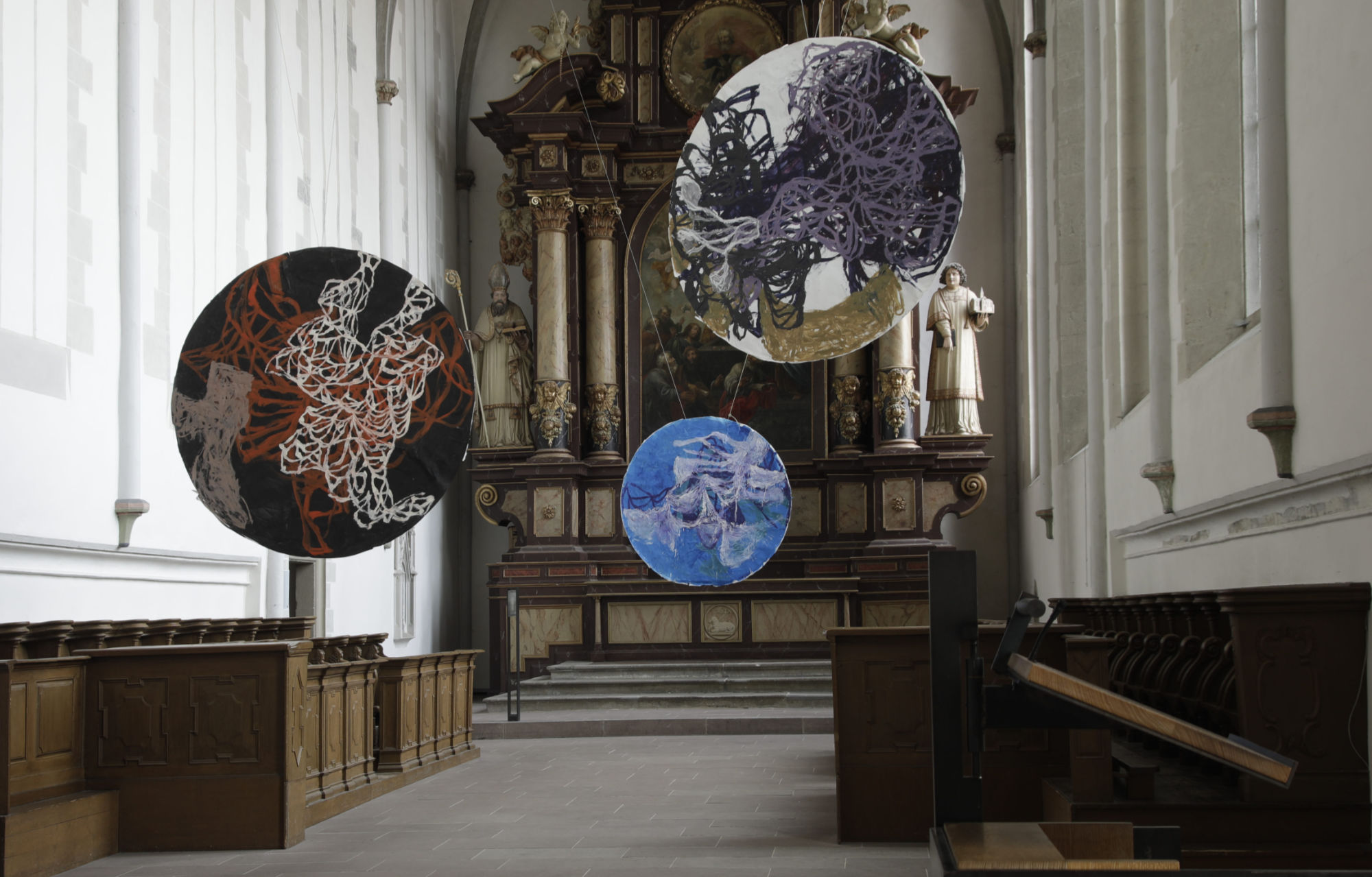 Axel Plöger installation von kreisförmigen Arbeiten in der Klosterkirche Warburg, Installationsasicht mit drei hängenden Bildern
